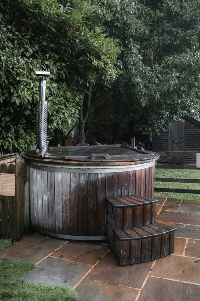Wooden hot tub with stove chimney in a back garden